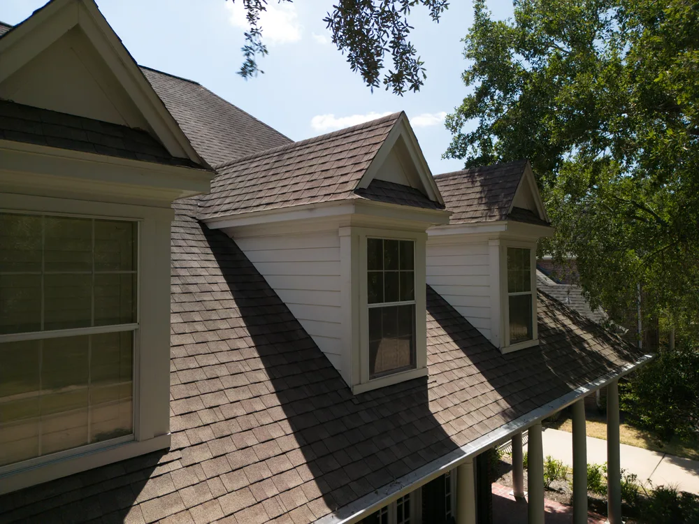 Brown architectural shingle roof with three dormer windows on a two-storey home.